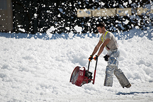 A professional man working in road side with snow blower