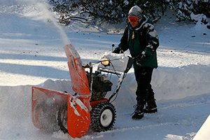 A man working with snow blower in front of his house